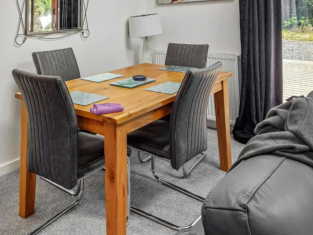 a wooden table with four chairs around it at Cairn View in Strachan