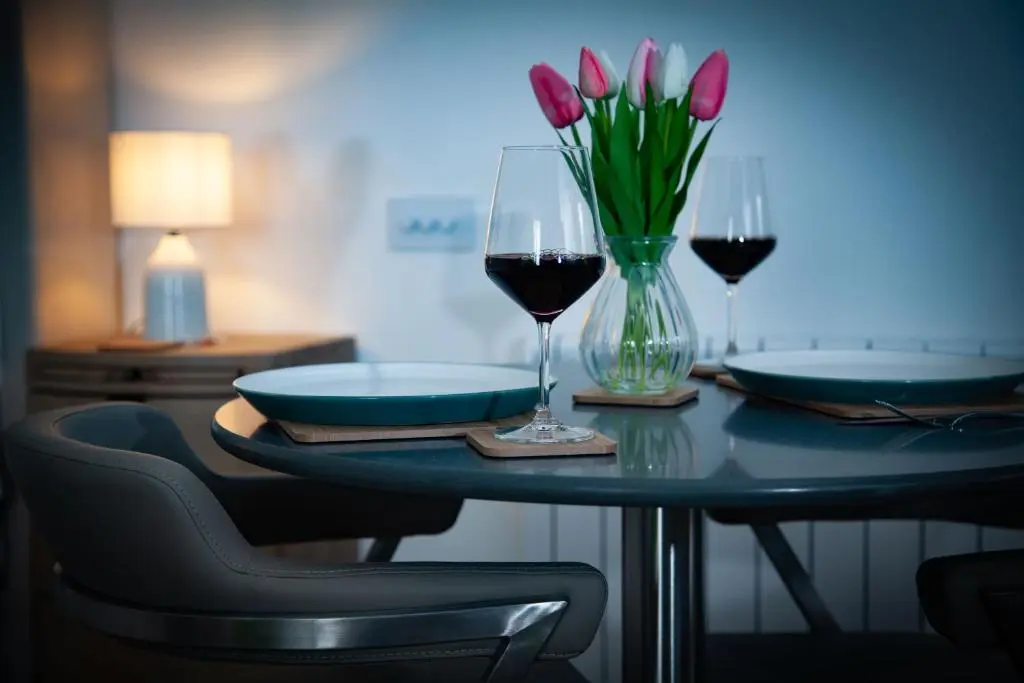 a table with two glasses of wine and a vase of flowers at Drumfin Cottage in Elgin