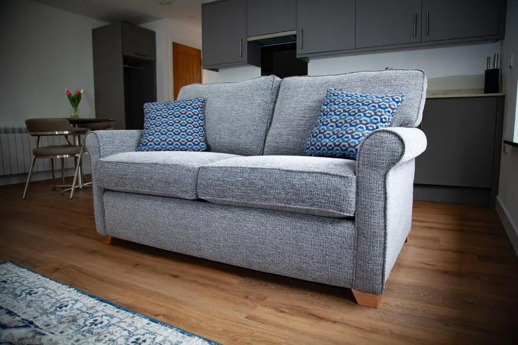 a gray couch with blue pillows in a living room at Drumfin Cottage in Elgin