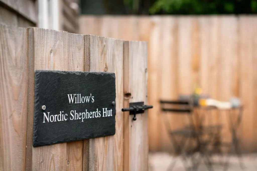 a sign on a wooden fence with a table at Willow's Nordic Shepherds Hut in Ballater