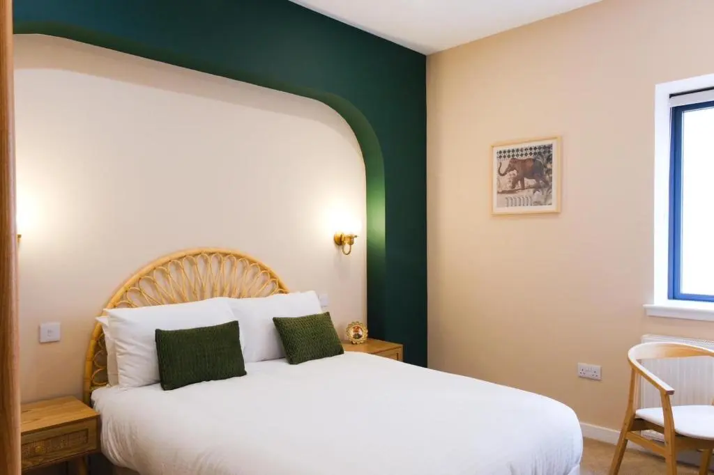 a bedroom with a white bed with a green accent wall at Inbhir Nis City Apartment in Inverness