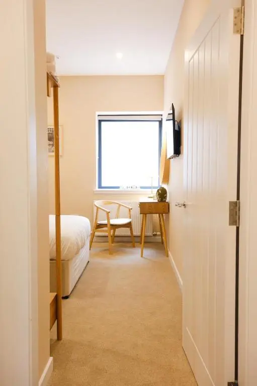 a bedroom with a bed and a desk and a window at Inbhir Nis City Apartment in Inverness