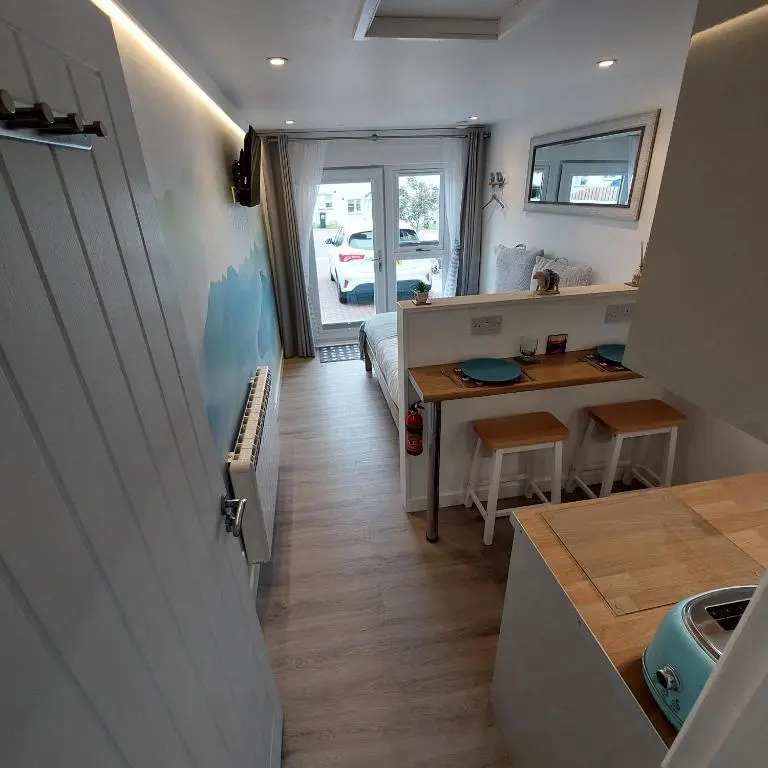 a small room with a bed and a table and a kitchen at The Snug - Cosy Retreat for Two in Inverness