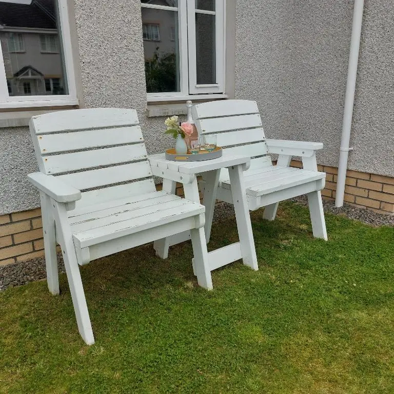 two white chairs and a picnic table on the grass at The Snug - Cosy Retreat for Two in Inverness