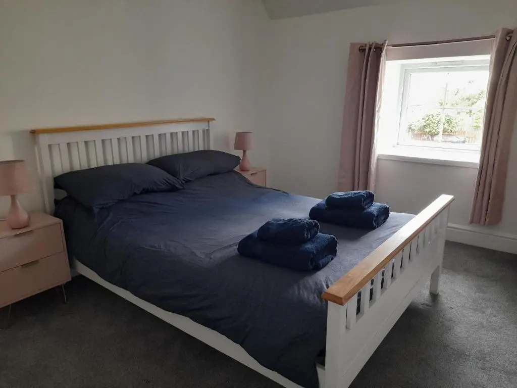 a bedroom with a bed with two blue pillows on it at Culbokie Inn on the NC500 in Culbokie