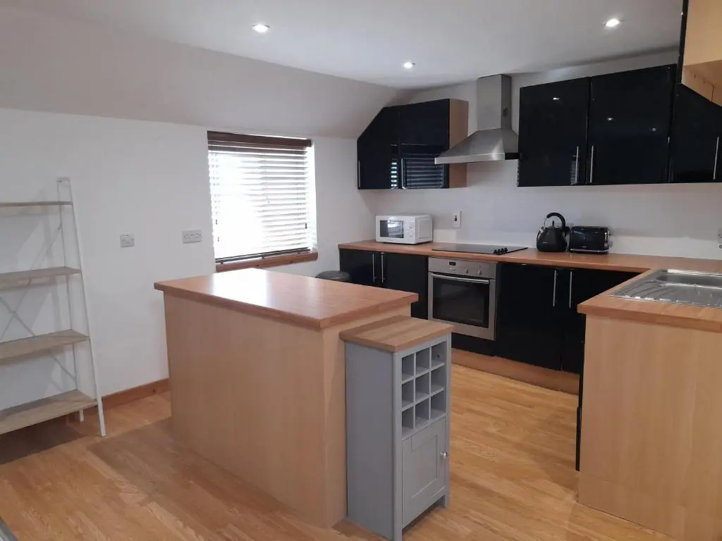 a kitchen with black cabinets and a wooden counter top at Culbokie Inn on the NC500 in Culbokie