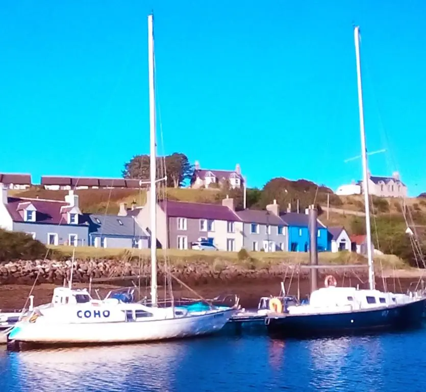 two boats docked in the water with houses in the background at Selkie House Song of the Sea in Helmsdale