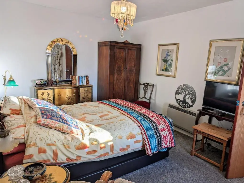 a bedroom with a bed and a tv and a table at Selkie House Song of the Sea in Helmsdale