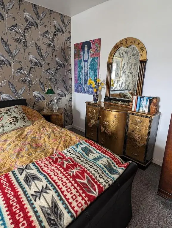 a bedroom with a bed and a dresser and a mirror at Selkie House Sea Song in Helmsdale