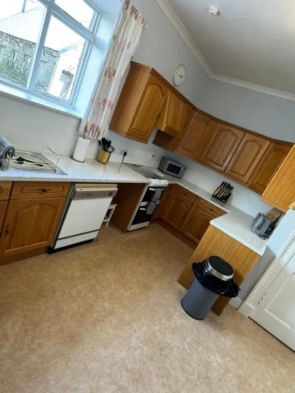 a small kitchen with wooden cabinets and a window at Spacious Harbour House in Wick