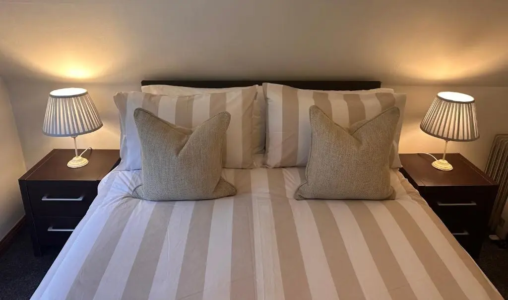 a bedroom with a bed with pillows and two lamps at Glen Lodges Rogart in Rogart