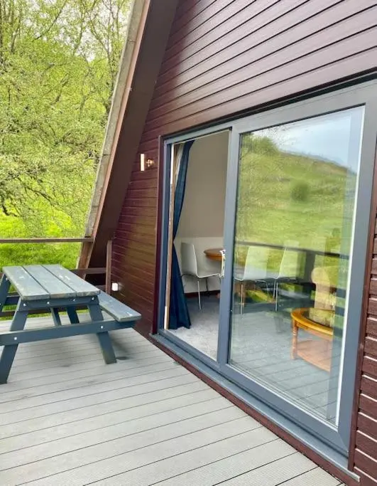 a deck with a picnic table and a sliding glass door at Glen Lodges Rogart in Rogart