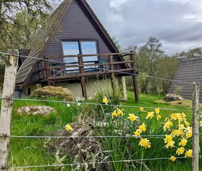 a house with a fence and flowers in front of it at Glen Lodges Rogart in Rogart