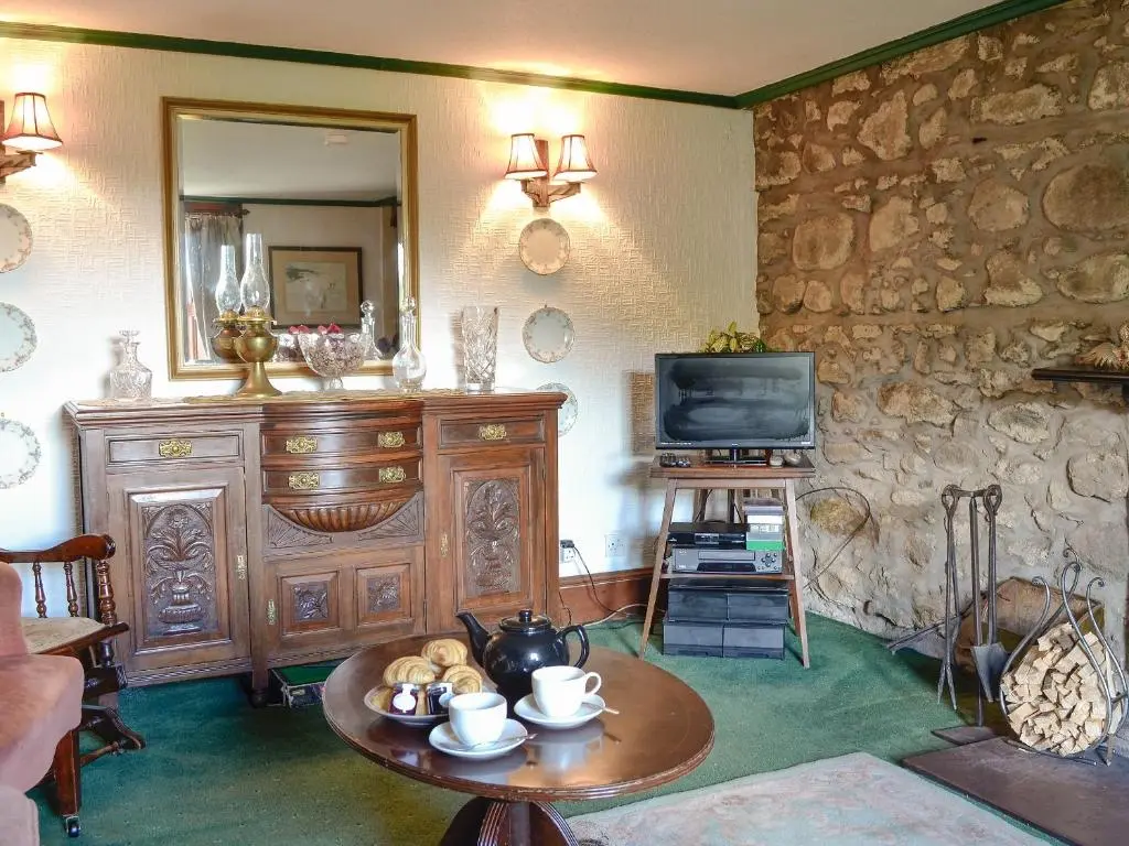 a living room with a table and a television at Dalvanie Mill - S4241 in Tulchan