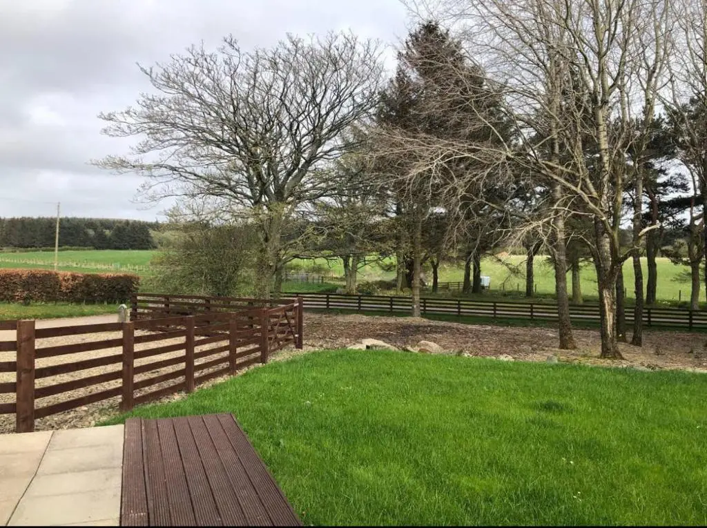 a park with a wooden fence and green grass at Backieley Lodge in Huntly