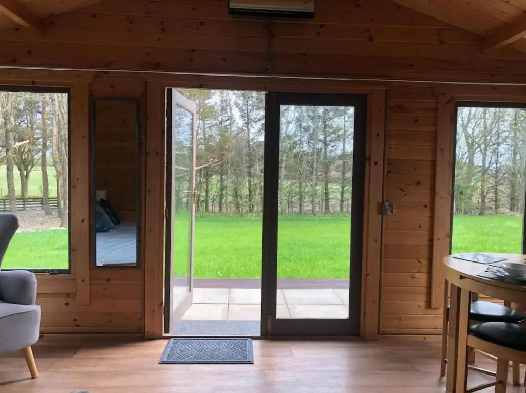 an open living room with sliding glass doors at Backieley Lodge in Huntly