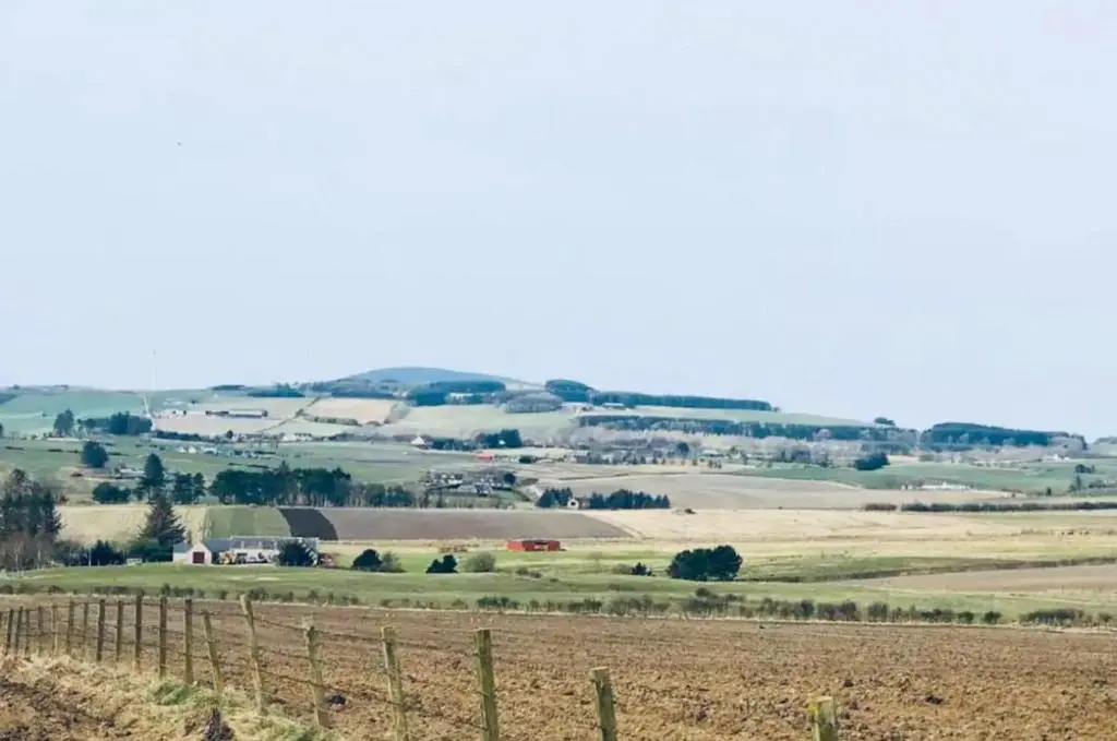 a view of a field with a fence in the foreground at Backieley Lodge in Huntly