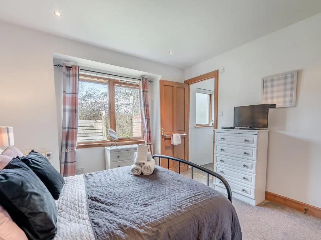 a bedroom with a bed and a tv and a dresser at Croftside House - S4401 in Inverdruie