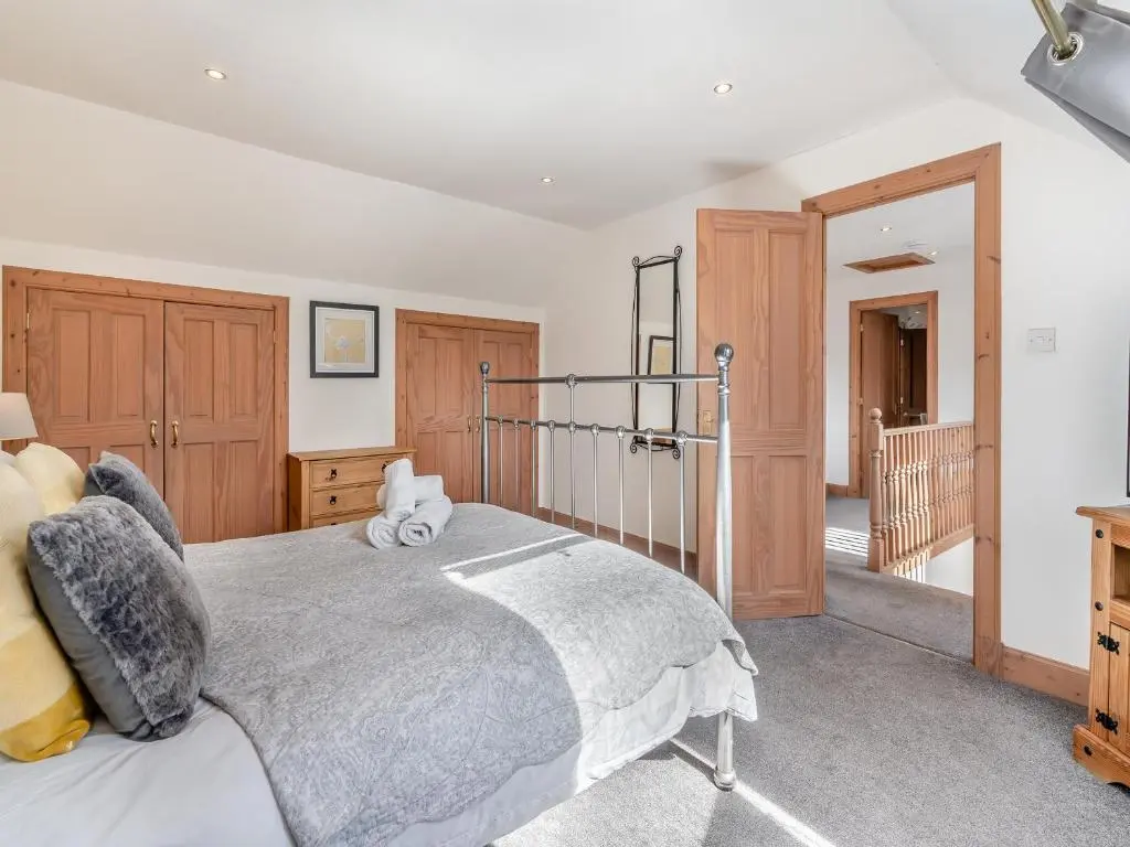 a bedroom with a large bed and wooden cabinets at Croftside House - S4401 in Inverdruie