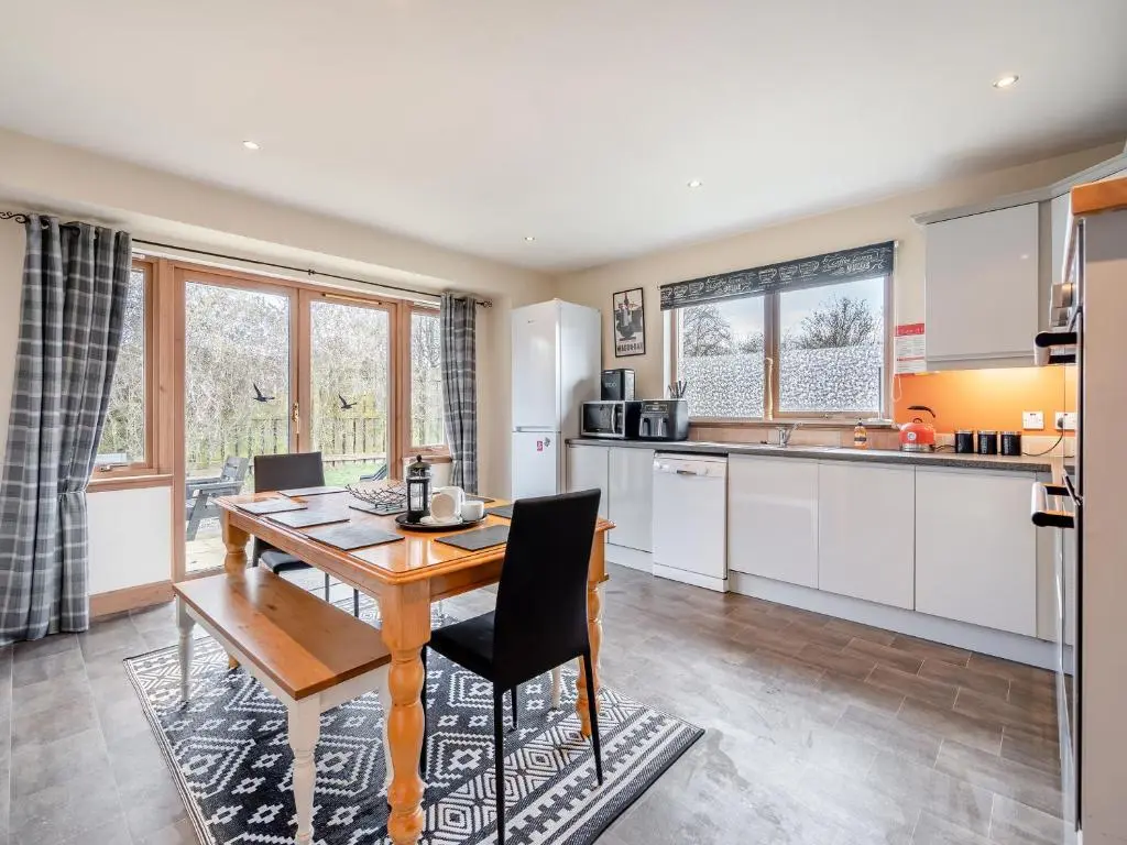a kitchen with a wooden table and chairs in a room at Croftside House - S4401 in Inverdruie