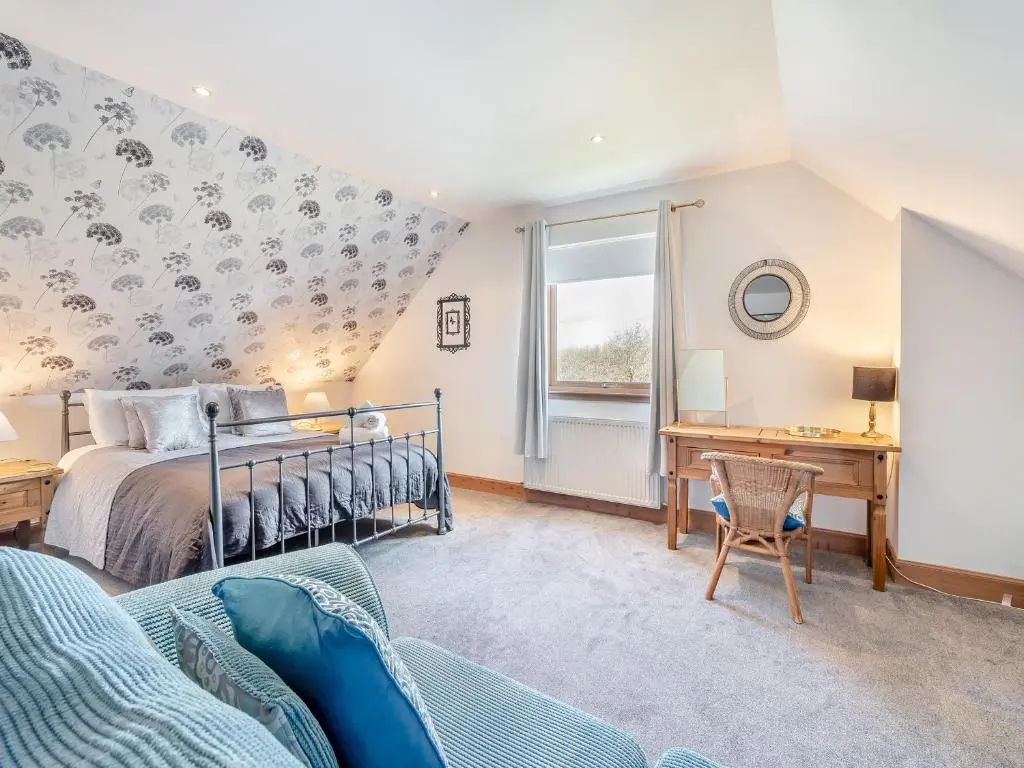 a bedroom with a bed and a desk at Croftside House - S4401 in Inverdruie