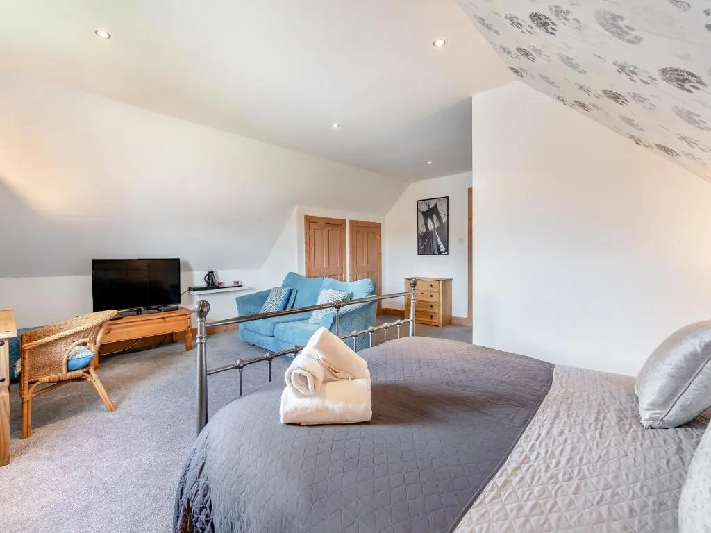 a bedroom with a bed and a living room at Croftside House - S4401 in Inverdruie