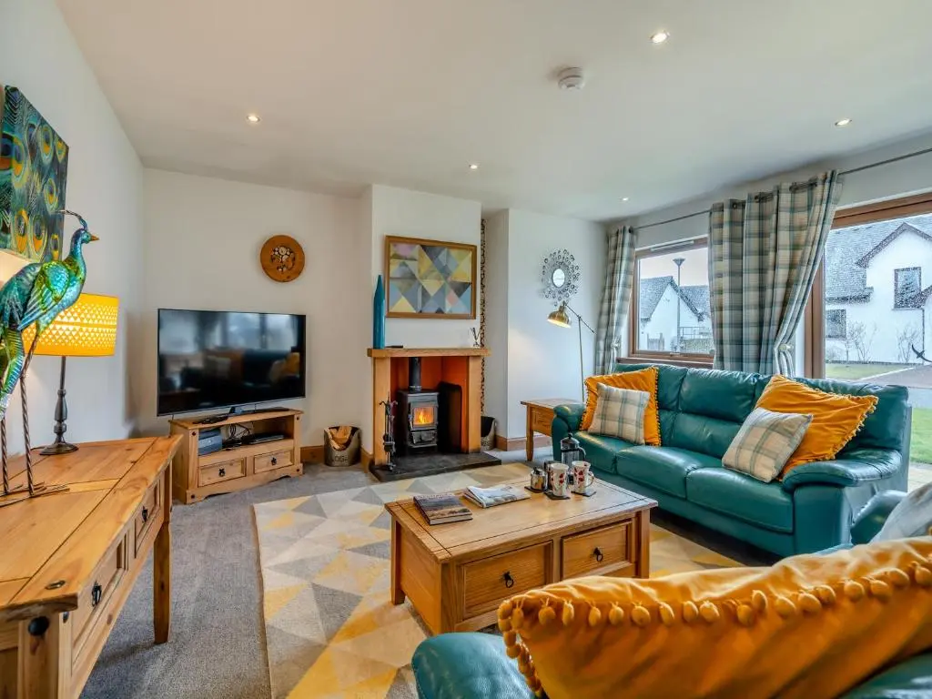 a living room with a blue couch and a tv at Cairn View - S4402 in Inverdruie