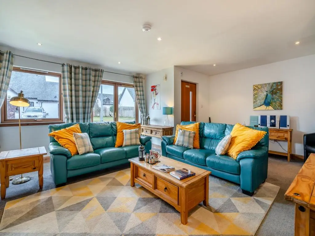 a living room with blue couches and a coffee table at Cairn View - S4402 in Inverdruie