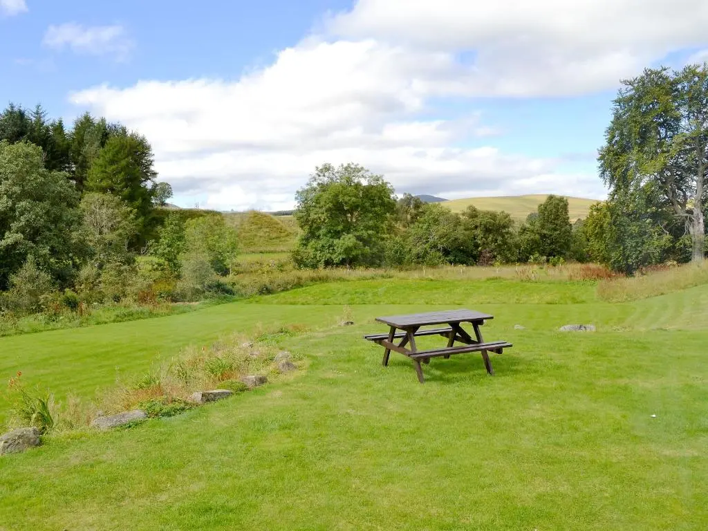 a picnic table in the middle of a field at Larch Cottage - S4428 in Kirkton of Glenisla