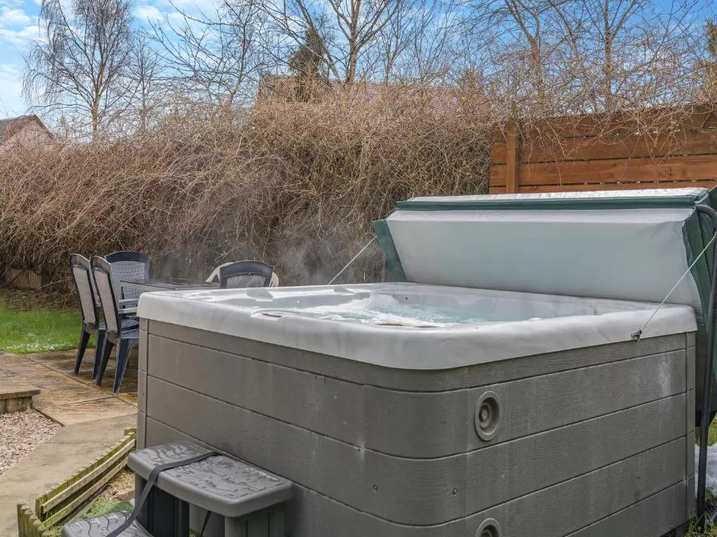 a hot tub in a backyard with a table and chairs at Coire Cas - S4538 in Inverdruie