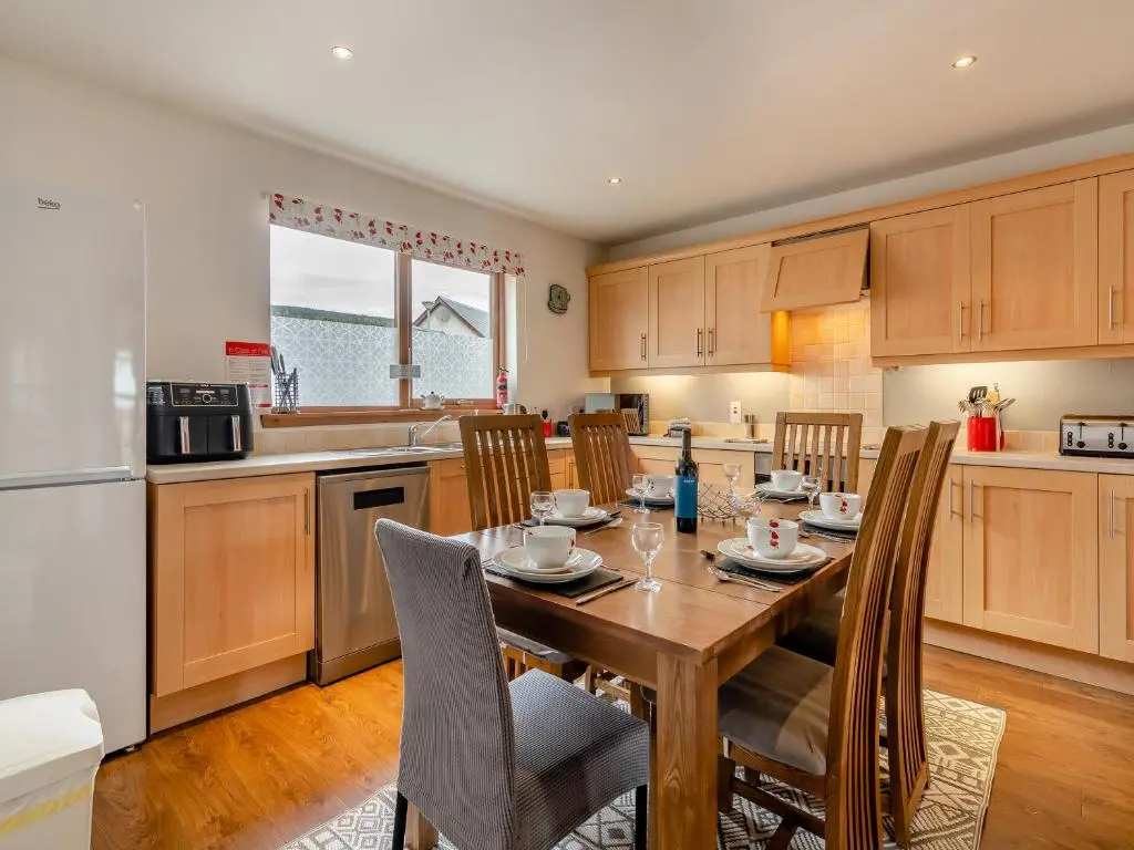 a kitchen with a wooden table and chairs in a kitchen at Clunnie Mor - S4615 in Aviemore