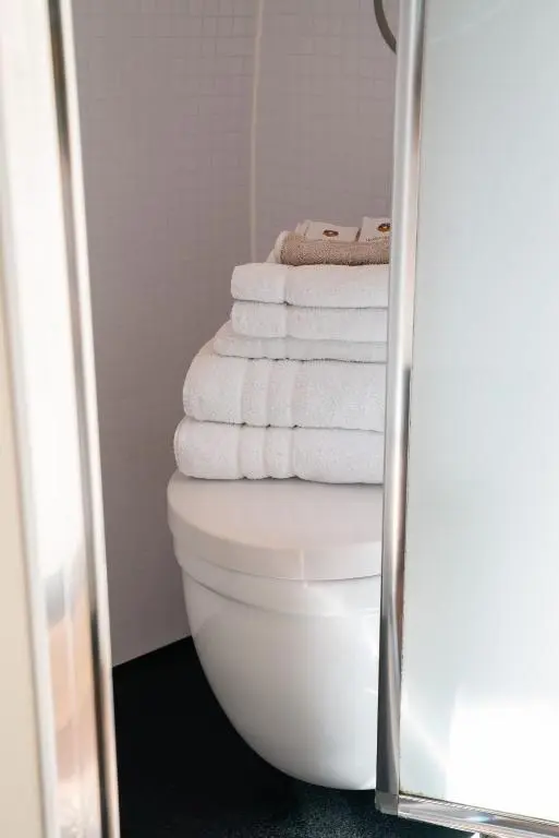 a stack of towels sitting on a toilet in a bathroom at Eriskay Guest House and Aviemore Glamping in Aviemore