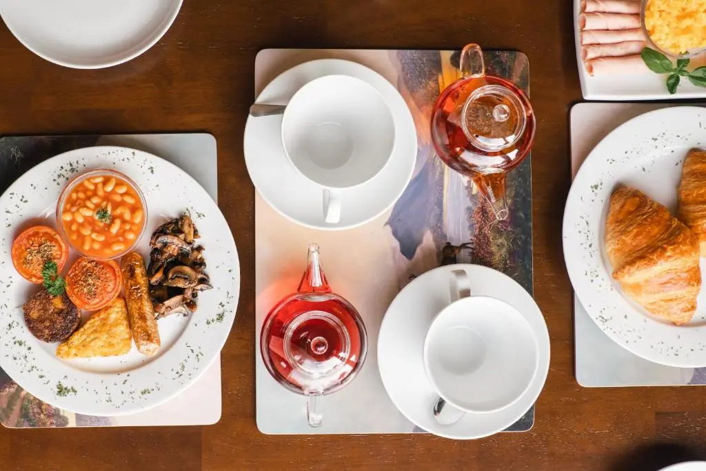 a table with plates of food and glasses of wine at Eriskay Guest House and Aviemore Glamping in Aviemore
