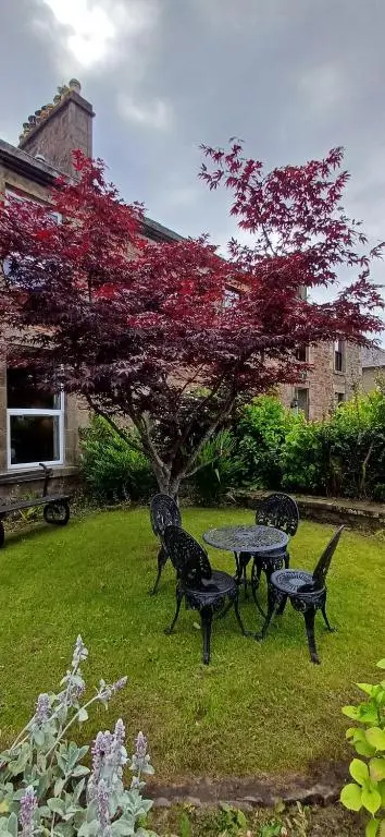 a picnic table and chairs in a yard with a tree at The Nest at Corbies Rest in Inverness