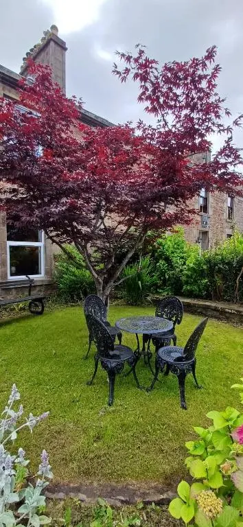 a picnic table and benches in a yard with a tree at The Nest at Corbies Rest in Inverness