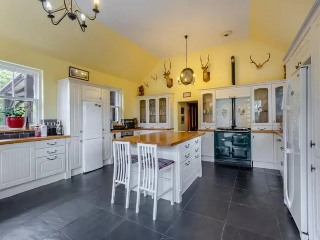 a kitchen with white cabinets and a table and chairs at The Doune, Luxury Traditional Country House with hot tub in Inverness
