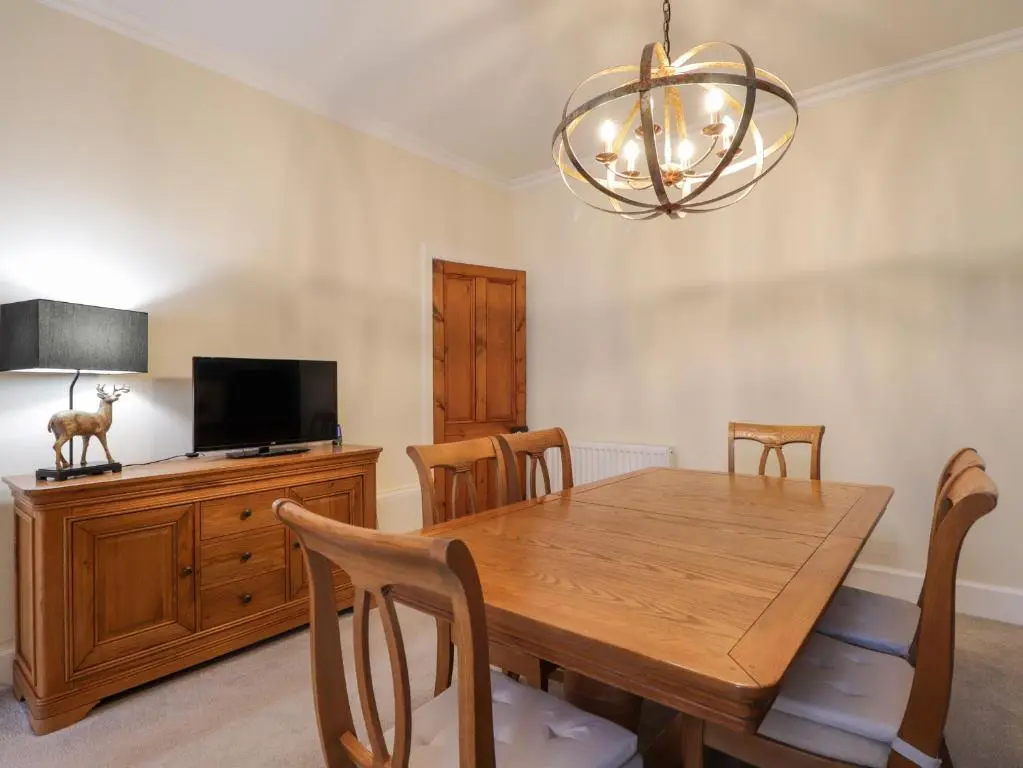 a dining room with a wooden table and a chandelier at Garry Isle in Inverness