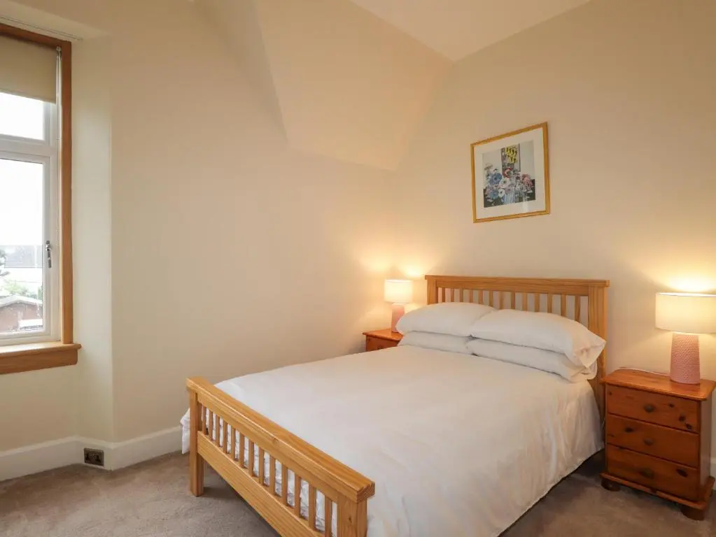 a bedroom with a bed with two night stands and two lamps at Garry Isle in Inverness