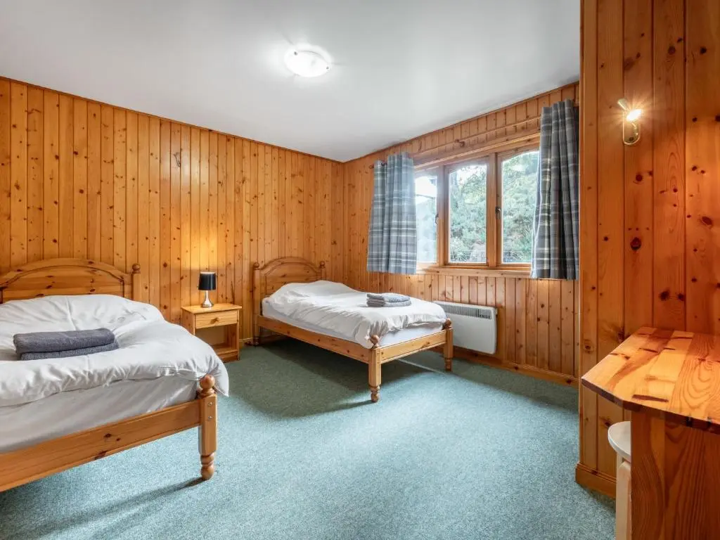 two beds in a room with wooden walls at Glomach Lodge at Lochletter Lodges in Drumnadrochit