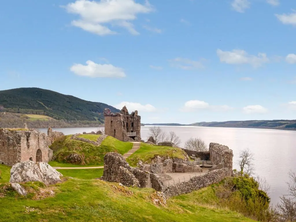 an old castle on a hill next to a body of water at Glomach Lodge at Lochletter Lodges in Drumnadrochit