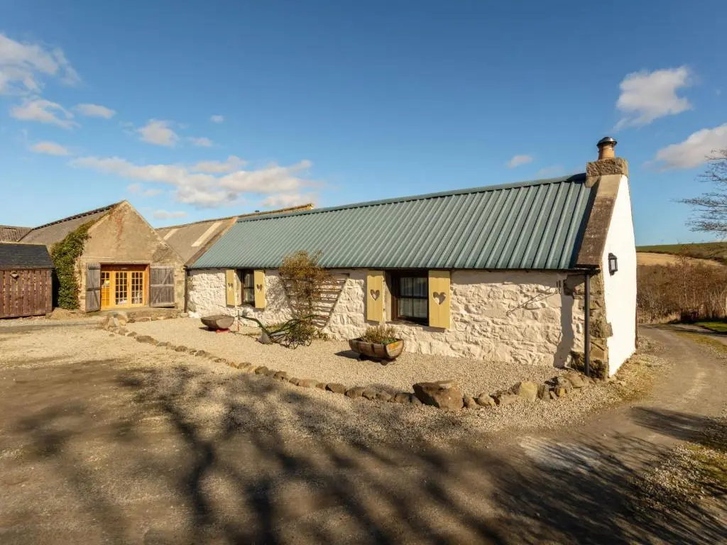 a stone cottage with a green roof on a road at Holiday Home Sunflower Cottage by Interhome in Marnoch