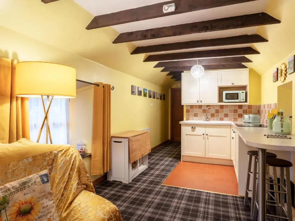 a small kitchen with yellow walls and wooden ceilings at Holiday Home Sunflower Cottage by Interhome in Marnoch