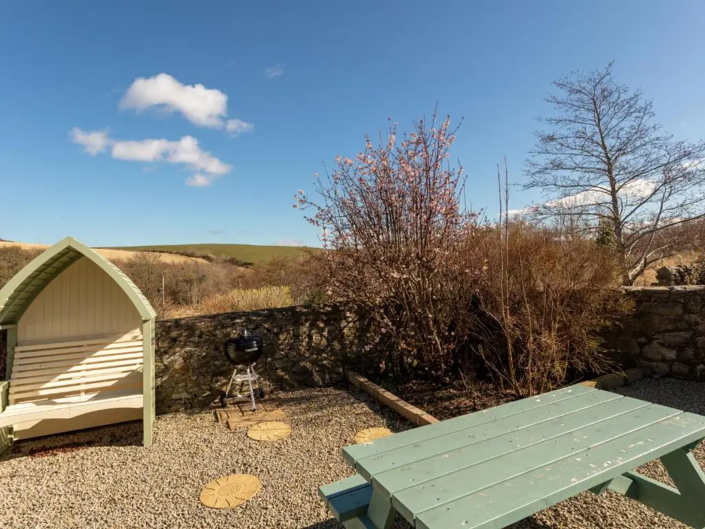 a picnic table and a camera in front of a wall at Holiday Home Sunflower Cottage by Interhome in Marnoch