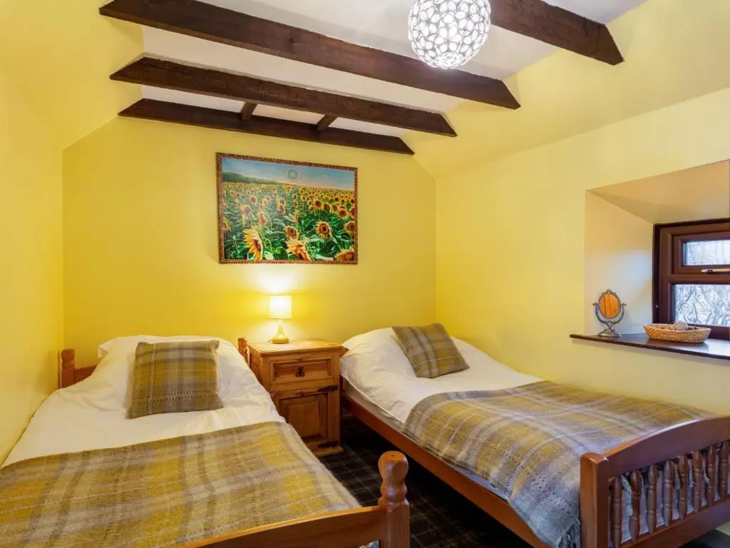 two beds in a room with yellow walls at Holiday Home Sunflower Cottage by Interhome in Marnoch