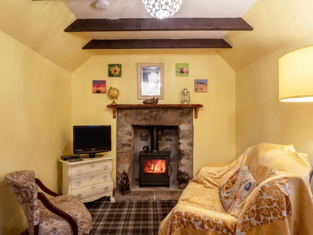 a living room with a fireplace and a couch at Holiday Home Sunflower Cottage by Interhome in Marnoch