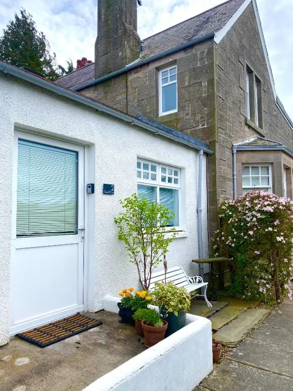 a white house with a white door and some plants at Glenburn, Peaceful Accommodation Fochabers in Fochabers