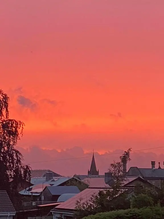 a sunset over a city with buildings and a church at Glenburn, Peaceful Accommodation Fochabers in Fochabers