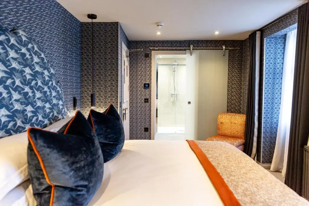 a bedroom with a large bed with blue pillows at Hotel 1881 of Speyside in Archiestown