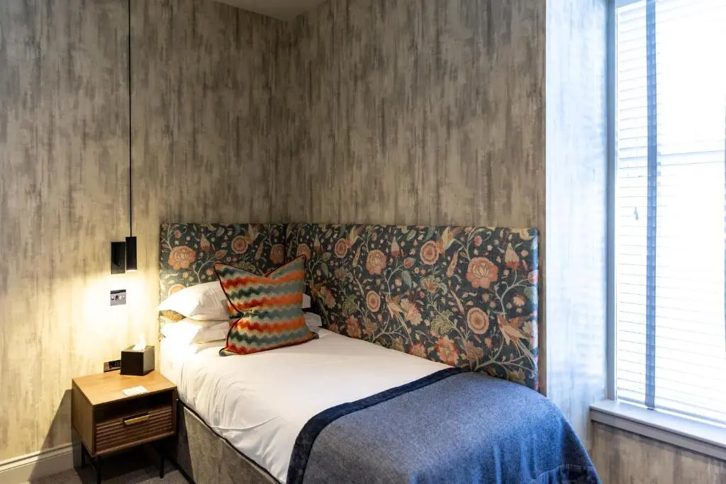 a bedroom with a bed with a patterned headboard at Hotel 1881 of Speyside in Archiestown
