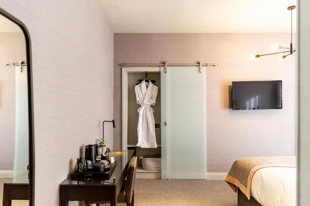 a bedroom with a bed and a dress hanging on a door at Hotel 1881 of Speyside in Archiestown